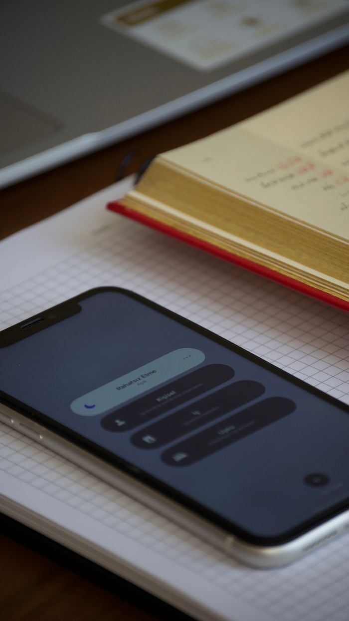 services-03 Smartphone on a grid notebook next to an open book in an indoor office setting.